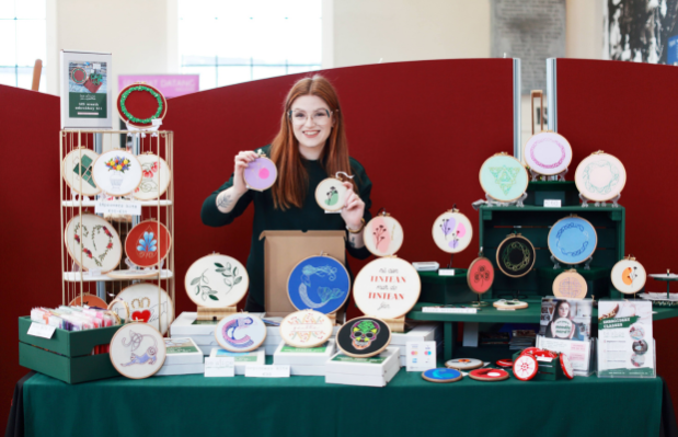 Alice is at her stall for the Christmas Fair surrounded by all of the embroidery she makes